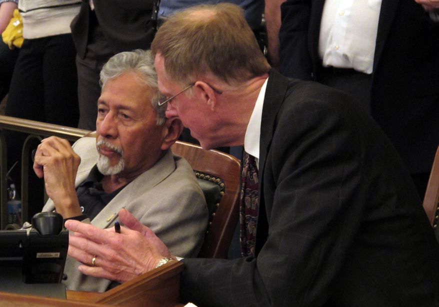 Kansas state Reps. Shanti Gandhi, left, a Topeka Republican, and David Crum, an Augusta Republican, confer during the House's debate on a school funding plan, Sunday, April 6, 2014, at the Statehouse in Topeka, Kan. The plan boosts aid to poor school districts but eliminates tenure for public school teachers. (AP Photo/John Hanna)