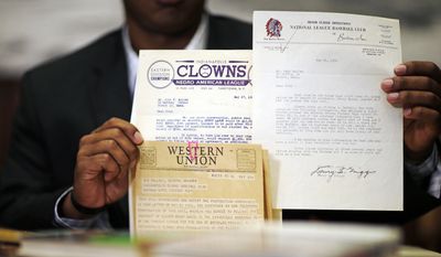 Emory University student Kyle Arbuckle, holds up some of the school's collection of Hank Aaron materials, Monday, April 7, 2014, in Atlanta. Arbuckle, along with classmates Warren Kember and Brett Lake teamed up last year to dig through the collection, donated in 2013 by a former scout for the Atlanta Braves, to create an exhibit opening on April 24 at the university’s Robert W. Woodruff Library. (AP Photo/David Goldman)