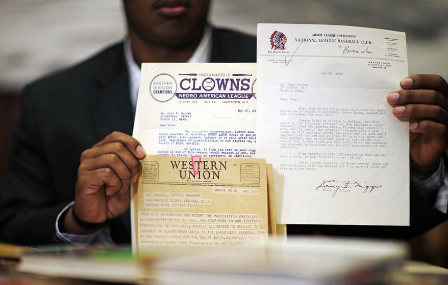 Emory University student Kyle Arbuckle, holds up some of the school's collection of Hank Aaron materials, Monday, April 7, 2014, in Atlanta. Arbuckle, along with classmates Warren Kember and Brett Lake teamed up last year to dig through the collection, donated in 2013 by a former scout for the Atlanta Braves, to create an exhibit opening on April 24 at the university’s Robert W. Woodruff Library. (AP Photo/David Goldman)