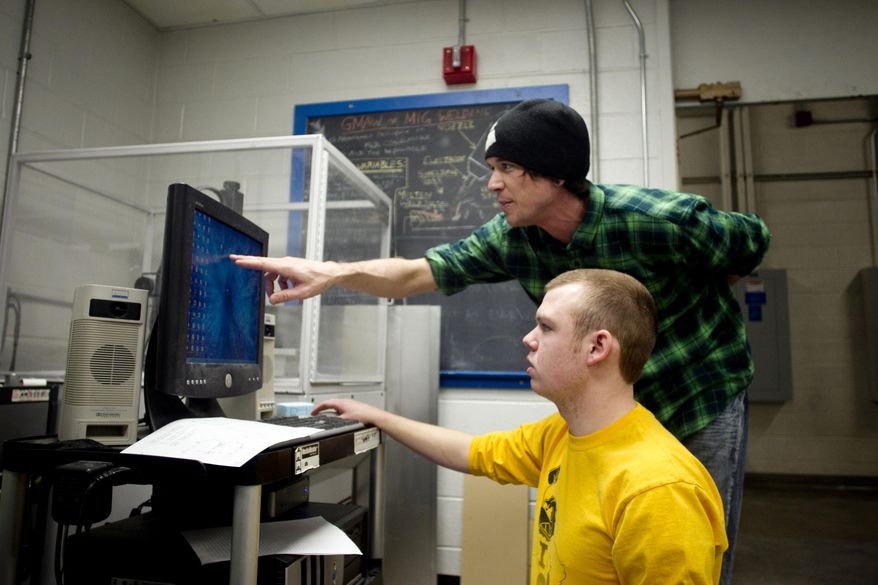 Cameron Dey receives instructions from Teaching Assistant Austin Krebill, right, in the Design for Manufacturing course at the University of Iowa Seamans Center for the Engineering Arts and Sciences in Iowa City on March 27, 2014. In the past 10 years, UI's College of Engineering has grown 70 percent — 30 percent in the past four years alone. Of those graduating, 98 percent leave school with jobs that have a median starting salary of more than $60,000. (AP Photo/Iowa City Press-Citizen, Benjamin Roberts) NO SALES