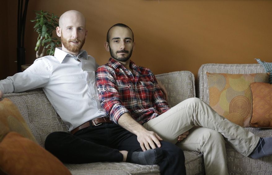 In this April 3, 2014, photo, Derek Kitchen, left, and Moudi Sbeity sit on their couch at their home, in Salt Lake City. The young couple that has become the face of gay marriage in Utah is an unlikely pair for the role. Kitchen and Sbeity were both raised in conservative religious families that shun gays, Kitchen in a Mormon home in Utah and Sbeity in a Muslim family in Lebanon. They each came out when they were 16 years old, worlds apart, and met six years later in college in Utah. They chose to become one of three couples as plaintiffs in the lawsuit challenging Utah’s same-sex marriage to publicly push back against religions that oppress gays and lesbians. (AP Photo/Rick Bowmer)