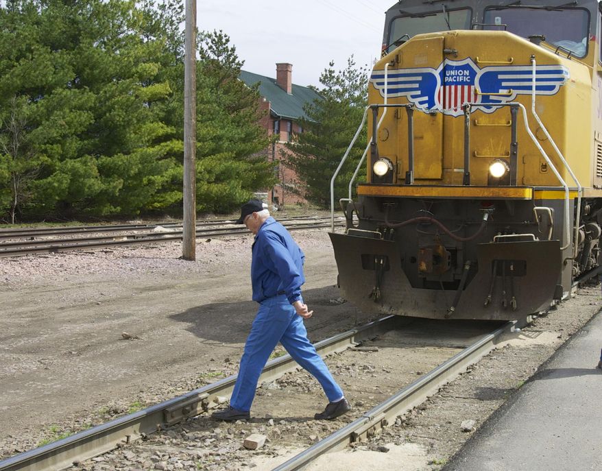 In this photo taken on April 7, 2010, a man crosses a railroad track in front of a stationary locomotive in Fremont, Neb. Regulators and the railroad industry are launching a new campaign Tuesday, April 8, 2014, to educate people about the dangers of train tracks. More people died trespassing on railroad tracks last year and more people were killed in crossing accidents. (AP Photo/Nati Harnik)
