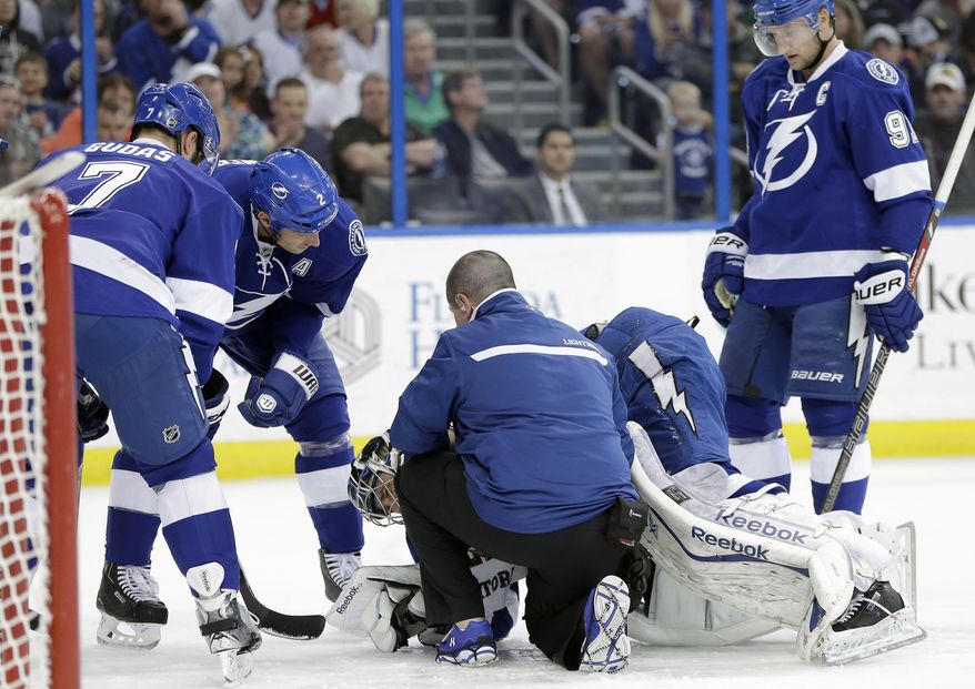 Tampa Bay Lightning defenseman Radko Gudas (7), of the Czech Republic, defenseman Eric Brewer (2) and center Steven Stamkos (91) look on as head athletic trainer Tommy Mulligan helps goalie Ben Bishop after he was injured during the first period of an NHL hockey game against the Toronto Maple Leafs Tuesday, April 8, 2014, in Tampa, Fla. Bishop left the game. (AP Photo/Chris O'Meara)