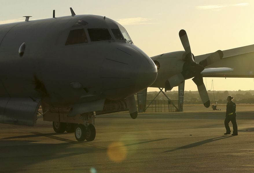 A flight crewman from a Royal Australian Air Force P-3 Orion walks towards the aircraft at RAAF Base Pearce as it arrives back from the on-going search operations for missing Malaysia Airlines Flight MH370 in Perth, Australia, Tuesday, April 8, 2014. Search crews have failed to relocate faint sounds heard deep in the Indian Ocean, possibly from the missing Malaysian jetliner's black boxes whose batteries are at the end of their life. (AP Photo/Rob Griffith)