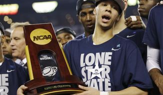 Connecticut guard Shabazz Napier holds the championship trophy after defeating Kentucky 60-54, at the NCAA Final Four tournament college basketball championship game Monday, April 7, 2014, in Arlington, Texas. (AP Photo/David J. Phillip)