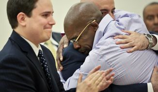 Jonathan Fleming, hugs his attorney Anthony Mayol while his other attorney Taylor Koss applaud in Brooklyn&#x27;s Supreme court, after a judge declared him a free man on Tuesday April 8, 2014 in New York.  Fleming, who spent almost a quarter-century behind bars for murder, was cleared of a killing that happened when he was 1,100 miles away on a Disney World vacation in 1989. (AP Photo/Bebeto Matthews)
