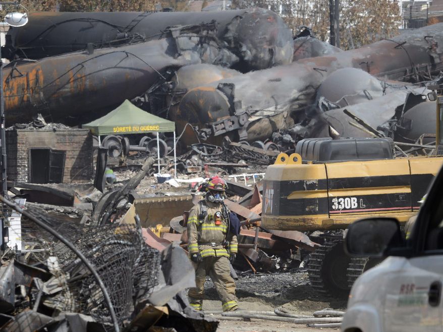 FILE - This July 6, 2013 file photo shows a worker, wearing protective gear moving though the wreckage of the oil train derailment and explosion in in Lac-Megantic, Quebec. Responding to a series of fiery train derailments, federal regulators said Wednesday they will propose that trains transporting crude oil have at least two-man crews and requirements aimed at preventing parked train cars from coming loose and causing an accident like one in July that killed 47 people. The Federal Railroad Administration had asked a freight rail industry advisory committee to make recommendations on whether two-man crews should be required, but the industry officials were unable to reach a consensus after working on the issue for months. Federal officials said they decided to move ahead with the two-crew member requirement anyway. (AP Photo/Ryan Remiorz, File, Pool)