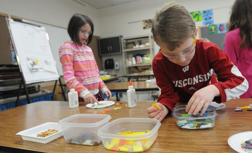 ADVANCED FOR RELEASE MONDAY, APRIL 14, 2014 Max Kese looks throughout the cut class as Zahara Buhrow, second graders, places glass on her self portrait. The art classes at Washington Elementary school in , Wis., are creating a lasting memory by making self portraits out of glass. The artwork will be displayed in a mural hung near the entrance of the school. (AP Photo/Oshkosh Northwestern Media, Joe Sienkiewicz)