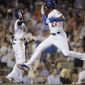 Los Angeles Dodgers&#39; Matt Kemp, right, leaps while greeting Dee Gordon, left, after scoring on a sacrifice fly by Justin Turner during the seventh inning of a baseball game against the Detroit Tigers in Los Angeles, Tuesday, April 8, 2014. (AP Photo/Kelvin Kuo)