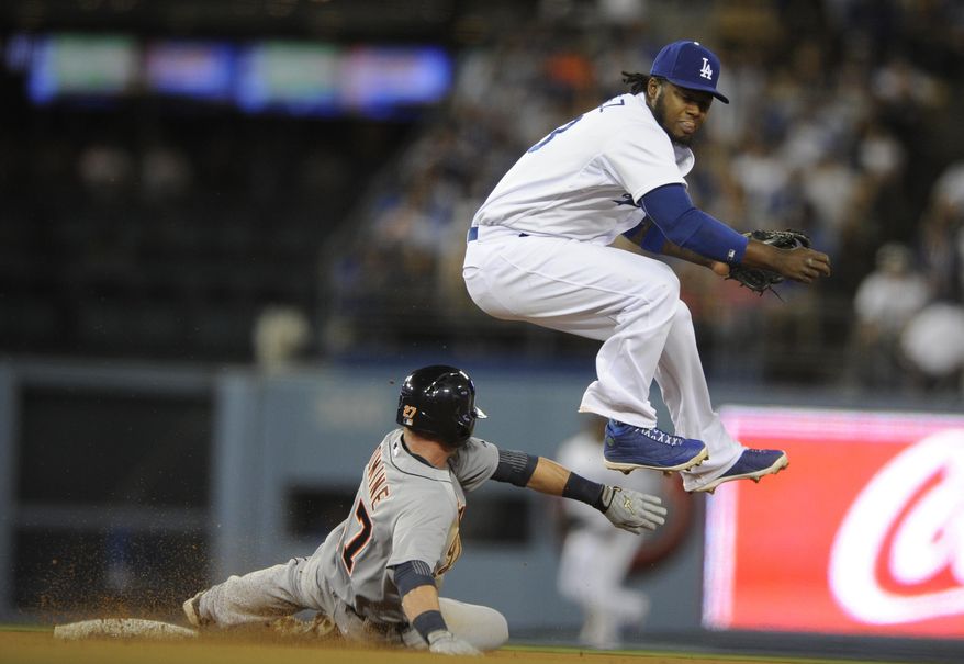 Los Angeles Dodgers shortstop Hanley Ramirez, right, jumps to avoid Detroit Tigers' Andrew Romine, left, after he threw to first to complete a double play during the eighth inning of a baseball game in Los Angeles, Tuesday, April 8, 2014. Rajai Davis was out at first. (AP Photo/Kelvin Kuo)