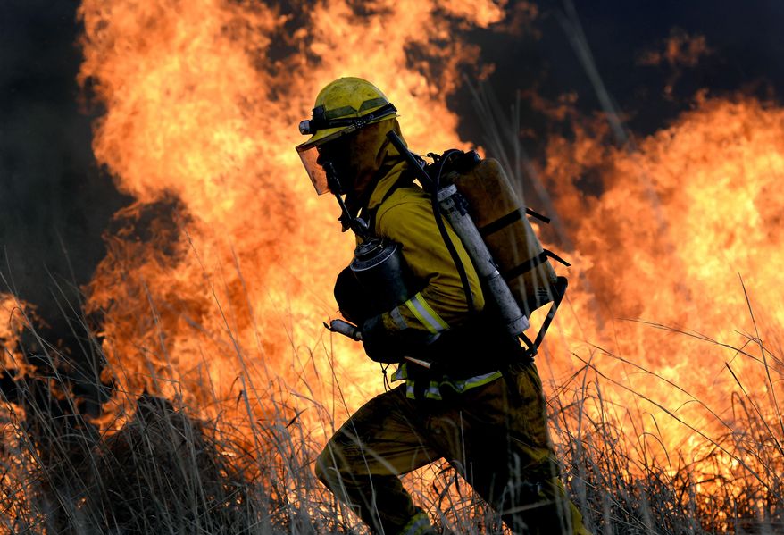 In this Tuesday, April 8, 2014 photo, fire crew member Scott Klotz runs out of danger as flames rise during a controlled burn in Meridian Township, Mich. The burn is expected to help improve habitat for the Henslow's sparrow. The Lansing State Journal reports the bird and many other types of wildlife use prairie habitat at the Davis-Foster Land Preserve. The sparrow is listed as endangered in Michigan. (AP Photo/The State Journal, Rod Sanford) NO SALES