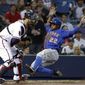 New York Mets&#x27; Eric Young Jr., right, slides into home plate to beat the throw to Atlanta Braves catcher Ryan Doumit to score off a single by teammate David Wright in the third inning of a baseball game, Thursday, April 10, 2014, in Atlanta. (AP Photo/David Goldman)