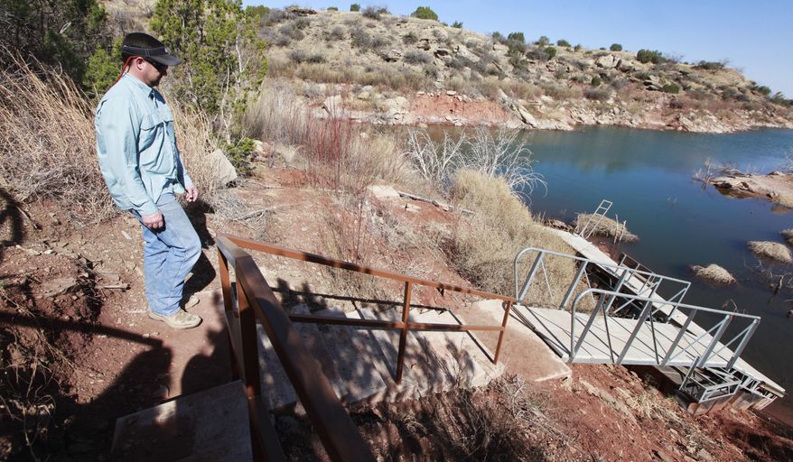 ADVANCE FOR RELEASE MONDAY, APRIL 14, 2014, AND THEREAFTER- In this March 18, 2014 photo, Eric Best looks out over his neighbors boat dock that no longer floats due to low lake levels at Lake Alan Henry in Texas. The lake lost roughly 4 billion gallons of water to evaporation in 2011, thanks to a lingering drought and sweltering temperatures and still more water is simply missing, according to federal government data. (AP Photo/Lubbock Avalanche-Journal, Stephen Spillman)