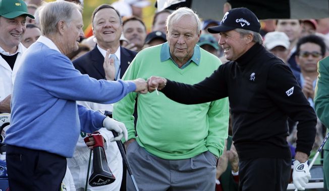 Arnold Palmer, center, watches as Jack Nicklaus, left, and Gary Player touch fists after Palmer hit his ceremonial drive on the first tee during the first round of the Masters golf tournament Thursday, April 10, 2014, in Augusta, Ga. (AP Photo/David J. Phillip) 