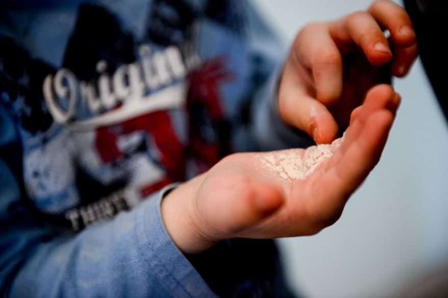 Boaz Kugler, 4, hold flour in his hand after crushing wheat kernels as he and other children learn how to make matzah bread at the Congregation Har Tzeon-Agudath Achim, Silver Spring, Md., Wednesday, April 9, 2014. (Andrew Harnik/The Washington Times)