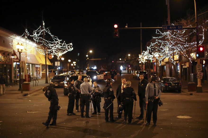 Police in riot gear stood guard following a celebration by University of Minnesota hockey fans after the Gophers last-second NCAA college hockey Frozen Four semifinal win, Friday, April 11, 2014, in Minneapolis, Minn. Hundreds of students and other hockey fans took to the streets in Dinkytown near campus to celebrate the victory over North Dakota Thursday night. (AP Photo/The Star Tribune, Jeff Wheeler)