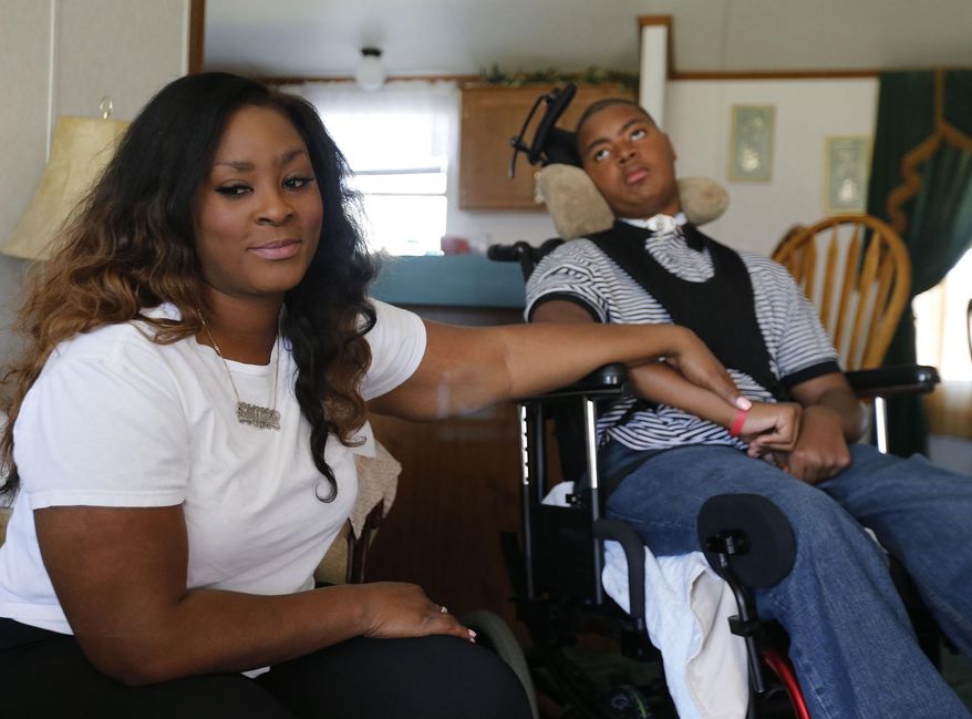 In this photo taken on March 26, 2014, Latisha Fields holds the hand of her son Ellis Ray Tripp, who is recovering from an oxygen deprivation injury, in New Bern, N.C. (AP Photo/The New Bern Sun Journal, Bill Hand)