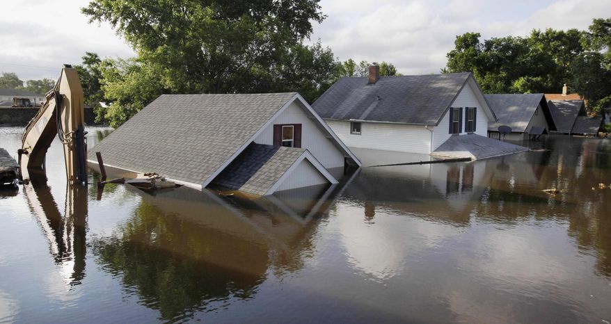 FILE - In this June 27, 2011 file photo, floodwaters from the Souris River surround homes and a back hoe near Minot State University in Minot, N.D. Officials in the Minot area say more state aid is needed for an $820 million flood protection project for the Souris River Basin unless federal funds materialize. Flooding in 2011 damaged or destroyed more than 4,000 structures in Minot. (AP Photo/Charles Rex Arbogast, File)