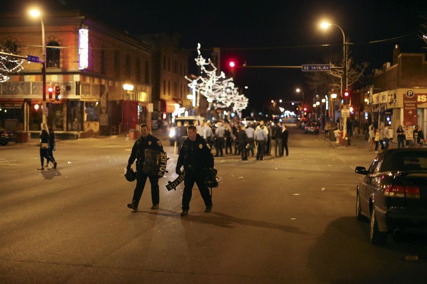 Police in riot gear stood guard following a celebration by University of Minnesota hockey fans following the Gophers last-second NCAA college hockey Frozen Four semifinal win, Friday, April 11, 2014, in Minneapolis, Minn. Hundreds of students and other hockey fans took to the streets in Dinkytown near campus to celebrate the victory over North Dakota Thursday night. (AP Photo/The Star Tribune, Jeff Wheeler)