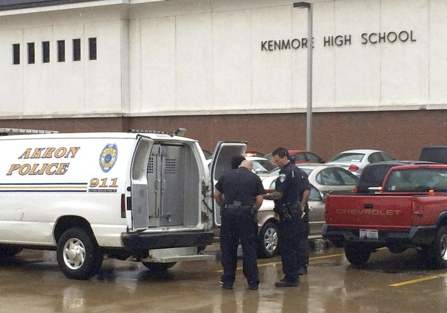 Akron police officers investigate a disturbance at Kenmore High School Friday, April 11, 2014 in Akron, Ohio. At least 12 students have been arrested in northeast Ohio after a fight broke out at the high school. A spokesman for Akron Public Schools says no one was seriously injured and no weapons were involved in the fight at Kenmore High School. (AP Photo/Akron Beacon Journal, Doug Livingston)