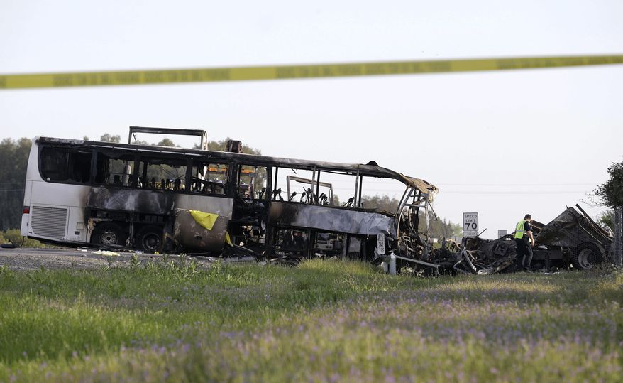 A California Highway Patrol Officer looks over the demolished cab of FedEx truck that crashed into a tour bus, at left, on Interstate 5 Thursday in Orland, Calif., Friday, April 11, 2014. At least ten people were killed and dozens injured in the fiery crash between the truck and a bus carrying high school students on a visit to a Northern California College. (AP Photo/Jeff Chiu)