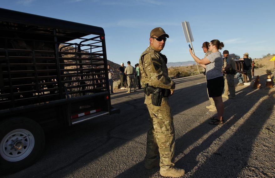 Federal law enforcement officers guard a convoy of cattle at the Lake Mead National Recreation Area near Overton, Nev. Thursday, April 10, 2014. Two people were detained while protesting the roundup of cattle owned by Cliven Bundy on the road. (AP Photo/Las Vegas Review-Journal, John Locher)