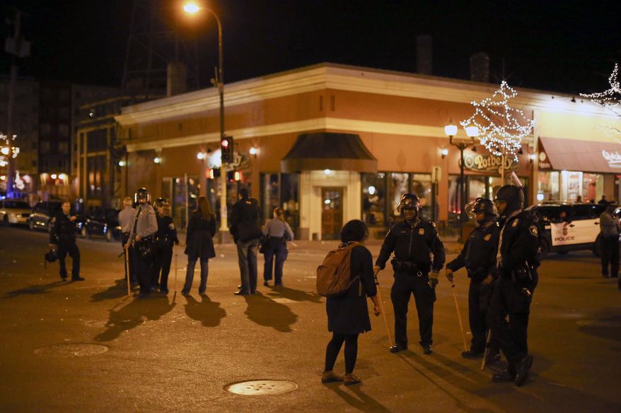 Police in riot gear stood guard following a celebration by University of Minnesota hockey fans after the Gophers last-second Frozen Four semifinal win, Friday, April 11, 2014, in Minneapolis, Minn. Hundreds of students and other hockey fans took to the streets in Dinkytown near campus to celebrate the victory over North Dakota Thursday night. (AP Photo/The Star Tribune, Jeff Wheeler)