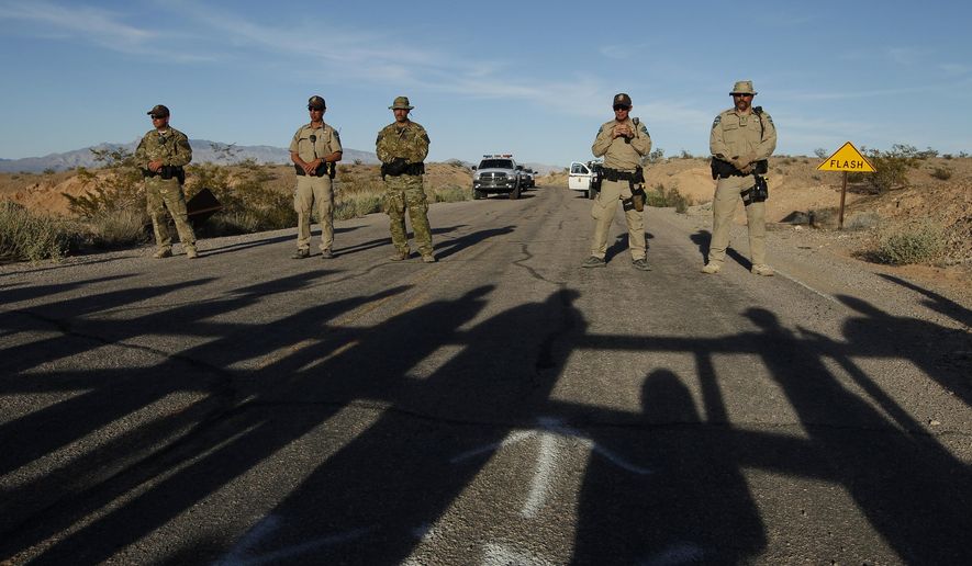 Federal law enforcement officers block a road at the Lake Mead National Recreation Area near Overton, Nev. Thursday, April 10, 2014. In the foreground are the shadows of protestors. Two people were detained while protesting the roundup of cattle owned by Cliven Bundy on the road. (AP Photo/Las Vegas Review-Journal, John Locher)