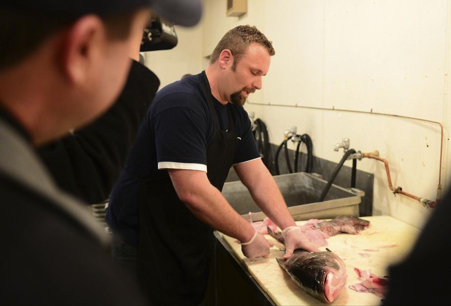 In this March 25, 2014 photo, Chef Clint Carter demonstrates ideas on how to prepare Asian carp at Dixon Seafoods in East Peoria, Ill., to give cooking ideas for local chefs who will be serving their own culinary creations at the Flying Fish Festival in July at East Peoria. The swarms of Asian carp that infest the Illinois River may not want to hear this, but they’re good to eat. (AP Photo/Journal Star, Fred Zwicky)