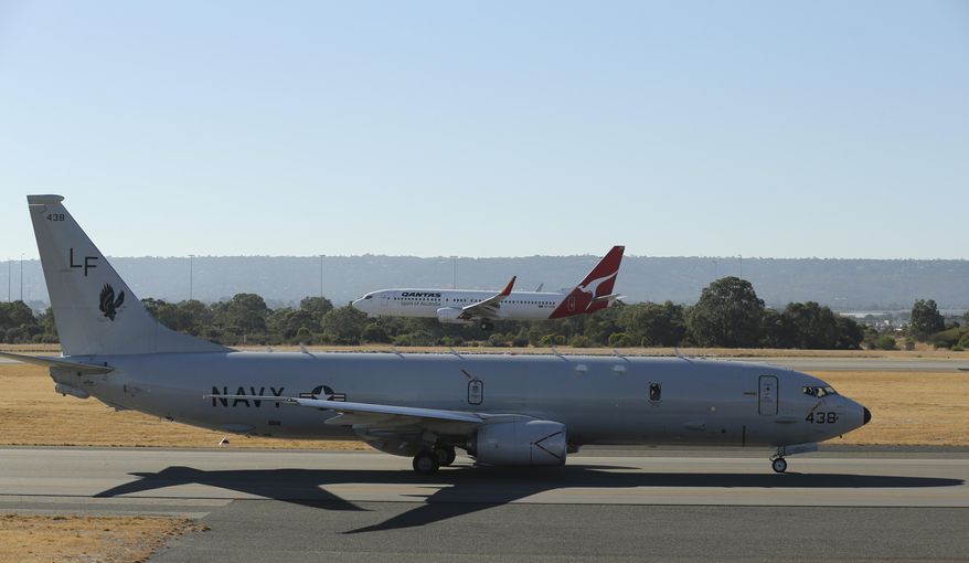 A Qantas jet lands behind a U.S. Navy P-8 Poseidon as it taxies along the runway at Perth Airport en route to rejoin the ongoing search operations for missing Malaysia Airlines Flight 370 in Perth, Australia, Friday, April 11, 2014. An air and sea hunt for the missing Malaysian jet resumed Friday in the same swath of the southern Indian Ocean where an underwater sensor made the fifth detection of a signal in recent days, raising hopes that searchers are closing in on what could be a flight recorder. (AP Photo/Rob Griffith)