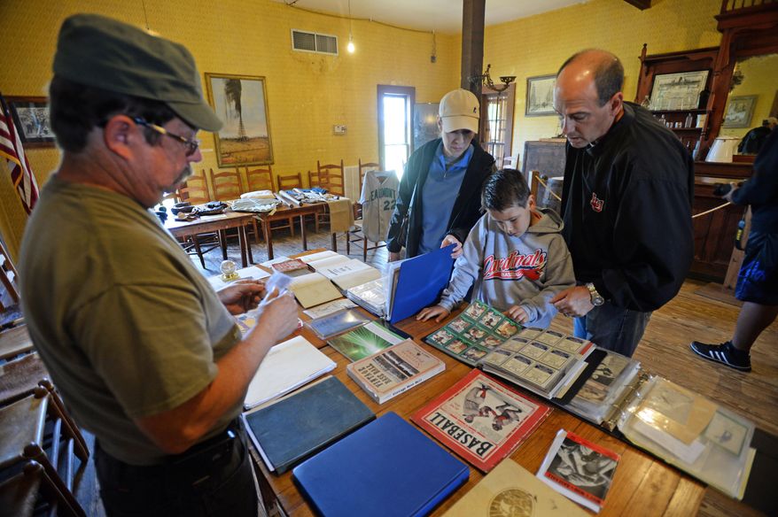 ADVANCE FOR USE MONDAY APRIL 14, 2014, AND THEREAFTER- In this April 5, 2014 photo, Don Smart, left, shows his baseball relics to Bryan Klutts, Evan Klutts, 8, and Sharon Klutts during a vintage baseball exhibit in Gladys City, Texas. (AP Photo/The Beaumont Enterprise, Guiseppe Barranco)