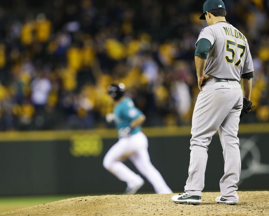 Oakland Athletics starting pitcher Tommy Milone, right, watches as Seattle Mariners&#x27; Mike Zunino rounds the bases on a two-run home run in the sixth inning of a baseball game, Friday, April 11, 2014, in Seattle. (AP Photo/Ted S. Warren)