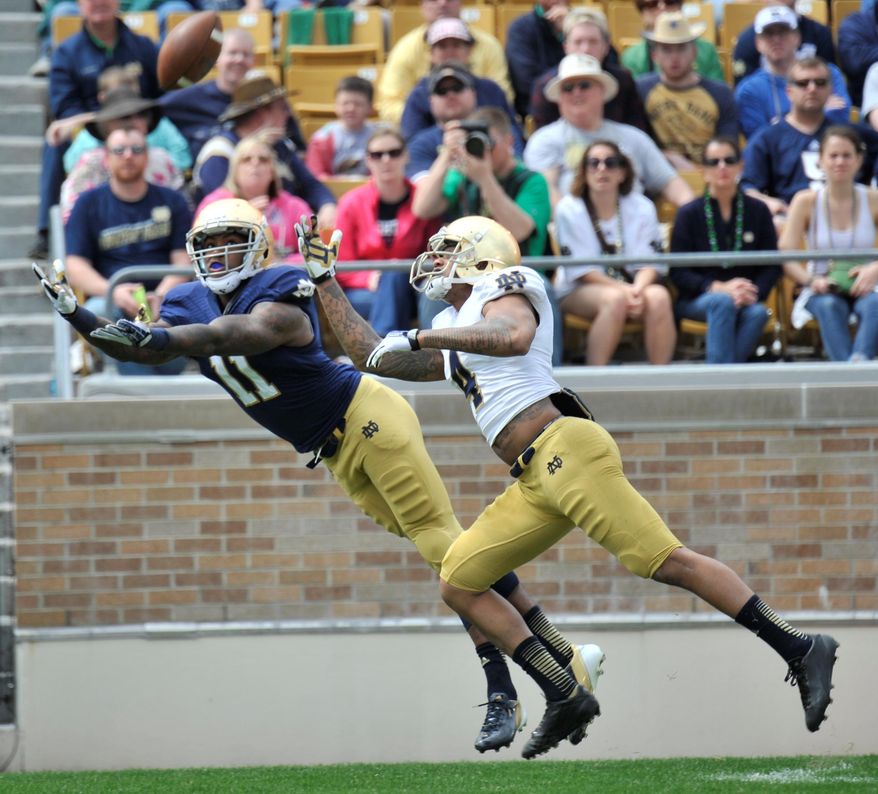 Notre Dame wide receiver Justin Brent reaches for a pass as safety Eilar Hardy defends during the second half of Notre Dame's spring NCAA college football game Saturday April 12, 2014 in South Bend, Ind. The Blue Gold game marks the end of spring football practice. (AP Photo/Joe Raymond)
