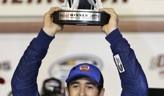 Chase Elliott raises the trophy in Victory lane after winning a NASCAR Nationwide series auto race at Darlington Speedway in Darlington, S.C., Friday, April 11, 2014. (AP Photo/Chuck Burton)