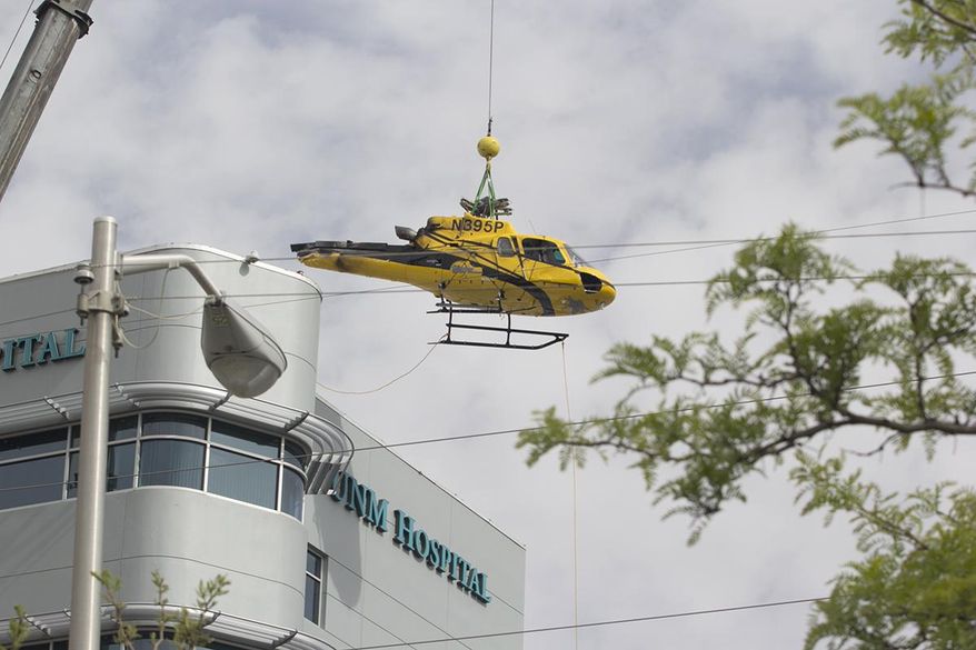 In this photo provided by the University of New Mexico Hospital, a medical helicopter is removed from the roof of University of New Mexico Hospital on Saturday, April 12, 2014 in Albuquerque, N.M. UNM spokesman Billy Sparks says the hospital remained fully operational during the process. Sparks says the hospital temporarily converted to using power from an internal generator, eliminating the potential for any accidents ignited by outside power sources. Sparks says a tail section was the first piece removed followed by jet fuel, which was channeled into special hazmat barrels, and then the helicopter's body. Officials are hoping to begin construction repairs to the roof by Saturday night. The helicopter crashed on Wednesday. (AP Photo/University of New Mexico Hospital courtesy of John Arnold)