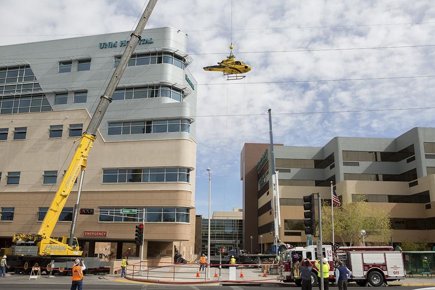 In this photo provided by the University of New Mexico Hospital, a medical helicopter is removed from the roof of University of New Mexico Hospital on Saturday, April 12, 2014 in Albuquerque, N.M. UNM spokesman Billy Sparks says the hospital remained fully operational during the process. Sparks says the hospital temporarily converted to using power from an internal generator, eliminating the potential for any accidents ignited by outside power sources. Sparks says a tail section was the first piece removed followed by jet fuel, which was channeled into special hazmat barrels, and then the helicopter's body. Officials are hoping to begin construction repairs to the roof by Saturday night. The helicopter crashed on Wednesday. (AP Photo/University of New Mexico Hospital courtesy of John Arnold)
