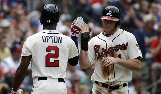 Atlanta Braves&#x27; Tyler Pastornicky, right, high-fives teammate B.J. Upton after scoring off a double by Jason Heyward in the second inning of a baseball game against the Washington Nationals, Sunday, April 13, 2014, in Atlanta. (AP Photo/David Goldman)