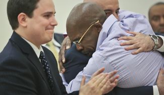 Jonathan Fleming, hugs his attorney Anthony Mayol while his other attorney Taylor Koss applaud in Brooklyn&#x27;s Supreme court, after a judge declared him a free man on Tuesday April 8, 2014 in New York.  Fleming, who spent almost a quarter-century behind bars for murder, was cleared of a killing that happened when he was 1,100 miles away on a Disney World vacation in 1989. (AP Photo/Bebeto Matthews)