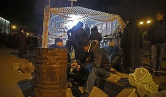 A man warms himself at a fire next to barricades in front of an entrance of the Ukrainian regional office of the Security Service in Luhansk, 30 kilometers (20 miles) west of the Russian border, in Luhansk, Ukraine, late Saturday, April 12, 2014.  Ukrainian Interior Minister Arsen Avakov described the unrest as &amp;quot;Russian aggression&amp;quot; and said Ukraine&#x27;s security officials would be gathering for an extraordinary meeting late Saturday evening. (AP Photo/Igor Golovniov)