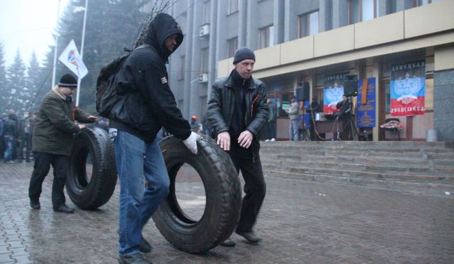 Pro-Russian activists roll tires to make barricades in front of the city government headquarters in Makeyevka, Ukraine on Sunday. (Associated Press)
