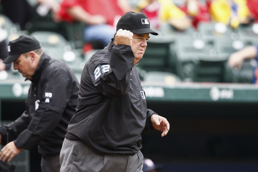 Umpire Joe West (22) signals an out after a challenged call at first base on a grounder by Texas Rangers' Shin-Soo Choo to Houston Astros second baseman Jose Altuve during the first inning of a baseball game, Sunday, April 13, 2014, in Arlington, Texas. The original call that Choo was safe was challenged. (AP Photo/Jim Cowsert)