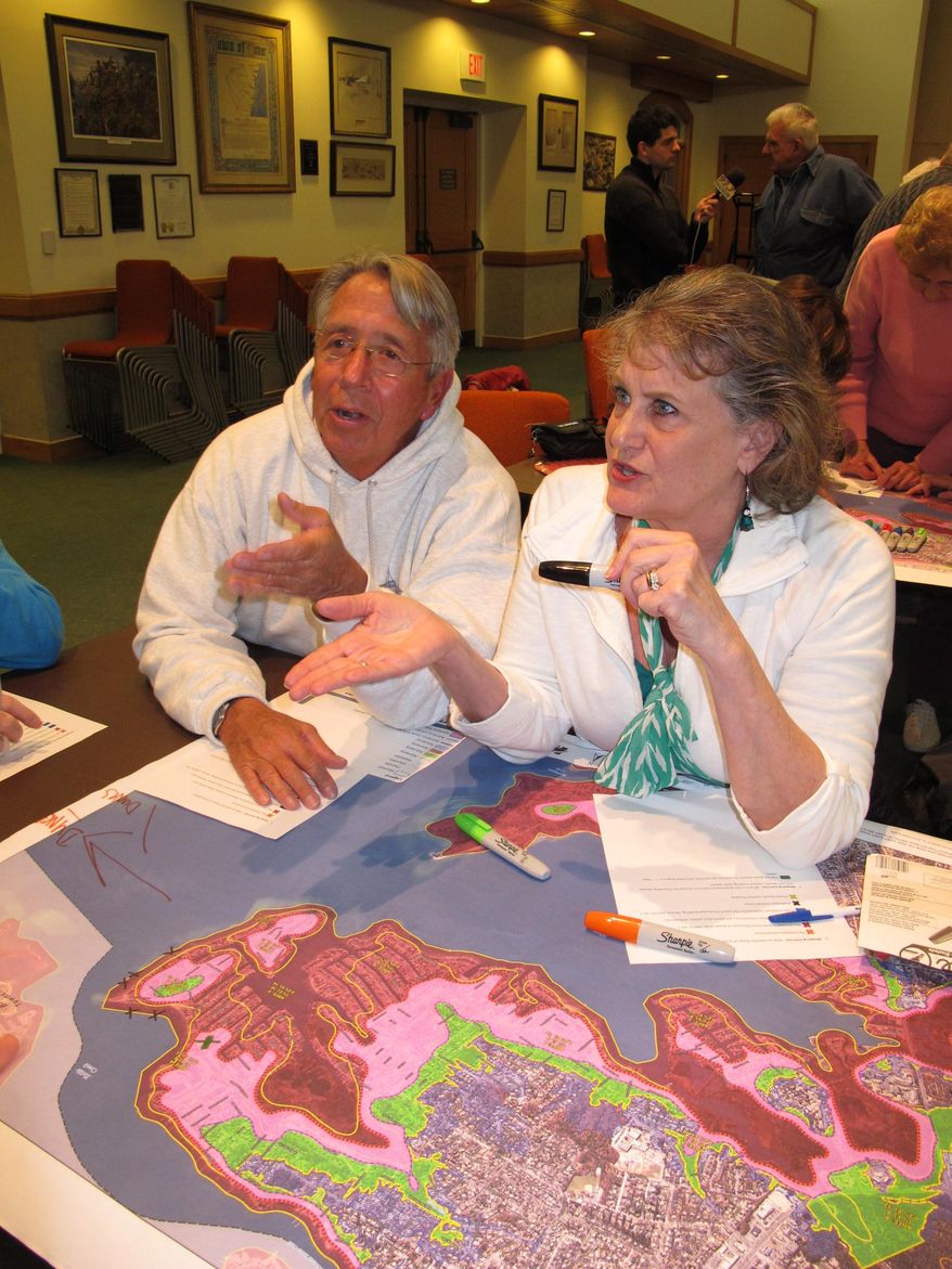In this March 18, 2014 photo, Jeff Coley, left, and Jo-Ann Herbst, right, review maps of Toms River N.J. showing flooding damage from Superstorm Sandy. They were at a hearing at the Toms River municipal building for residents to make suggestions on how to protect against future storms. Ideas included building dunes, adding bulkheading, better securing boats and floating docks, and monitoring the slope of homeowners' properties to avoid channeling water into low-lying areas. (AP Photo/Wayne Parry)