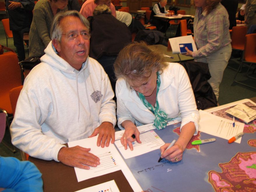 In this March 18, 2014 photo, Jeff Coley, left, and Jo-Ann Herbst, right, review maps of Toms River N.J. showing flooding damage from Superstorm Sandy. They were at a hearing at the Toms River municipal building for residents to make suggestions on how to protect against future storms. Ideas included building dunes, adding bulkheading, better securing boats and floating docks, and monitoring the slope of homeowners' properties to avoid channeling water into low-lying areas. (AP Photo/Wayne Parry)