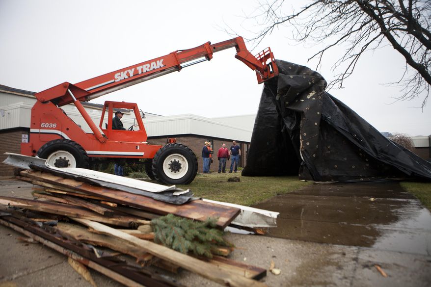 Workers clean up a roof that blew off of the gymnasium at Kent City High School after a storm in Kent City, Mich., Sunday, April 13, 2014. A wave of severe thunderstorms has blown across the southern half of Michigan, knocking out power to at least 174,000 homes and businesses and shutting down parts of two interstate highways because of fallen power lines. (AP Photo/The Grand Rapids Press, Lauren Petracca) ALL LOCAL TV OUT; LOCAL TV INTERNET OUT