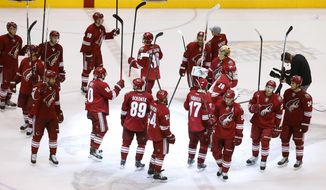 The Phoenix Coyotes players wave their sticks as they acknowledge the crowd after an NHL hockey game against the Dallas Stars on Sunday, April 13, 2014, in Glendale, Ariz.  The Coyotes defeated the Stars 2-1. (AP Photo/Ross D. Franklin)