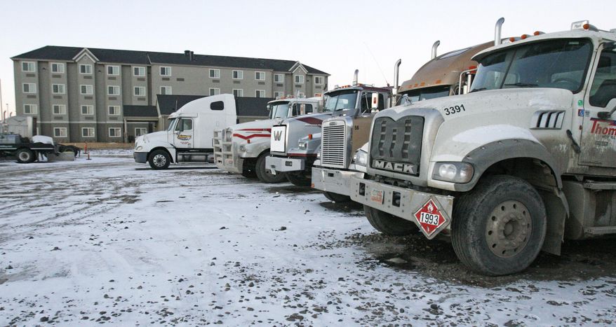 Trucks sit in a parking lot outside one of many newer multi-story hotels in Williston, N.D. on Tuesday, Feb. 25, 2014. Williston is the hub for the Bakken shale fields oil boom in North Dakota. Because of a housing shortage, the hotels often serve as temporary housing for oil workers. Big money is raining down in small towns. But the bonanza suddenly flourishing here has also brought with it a dark side: a growing trade in meth, heroin, cocaine and marijuana, drug cartels and newfound violence. (AP Photo/Martha Irvine)