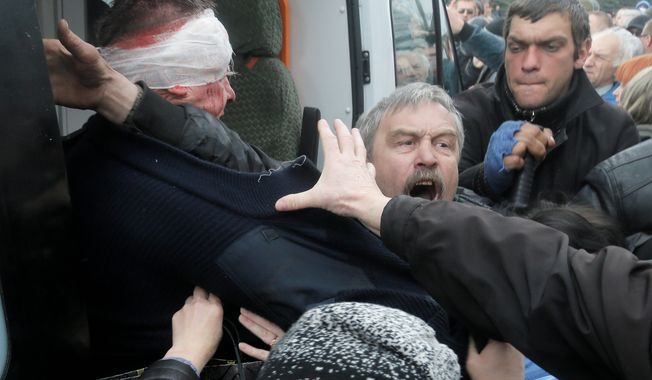 A man tries to protect a Ukrainian police officer beaten by a pro-Russian mob that stormed a police station in Horlivka, eastern Ukraine, Monday. A pro-Russian mob seized a police building in yet another city in Russian-leaning eastern Ukraine, defying government warnings that it was preparing to act against the insurgents. (Associated Press)