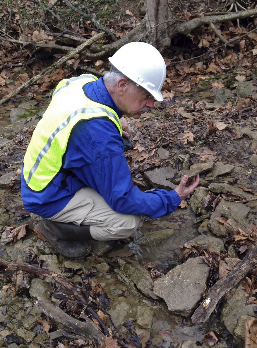 Bob Mason, stewardship manager for the Great Parks of Hamilton County, checks rocks for signs of oil residue at the parks’ Oak Glen Nature Preserve near Cincinnati, Monday, April 14, 2014. Parks officials say about 80 to 90 percent of the 20,000 gallons of crude oil that leaked from a pipeline has been removed, but they are continuing to search for oil remaining in soil and water at the site. (AP Photo/Lisa Cornwell)