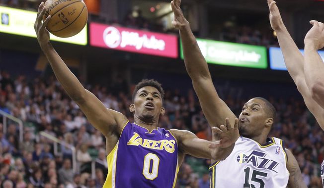 Los Angeles Nick Young (0) lays the ball as Utah Jazz&#x27;s center Derrick Favors (15) defends in the second quarter during an NBA basketball game Monday, April 14, 2014, in Salt Lake City, Utah. (AP Photo/Rick Bowmer)