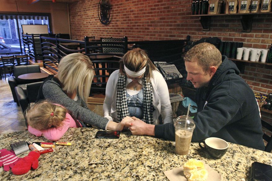 Patrick Johnsen prays with friends at a coffee shop in Williston, N.D. on Wednesday, Feb. 26, 2014. Johnsen, 29, came to the Bakken in 2010 to escape drugs. He'd been heavy into meth and crack back home in the Chicago suburbs and decided to start over, moving to North Dakota. He arrived with a mountain of debts and $11.72 in his pocket. He turned things around, working on an oil rig, and has been sober since September 2012. He attends a twice-weekly support group of recovering substance abusers and stays out of bars. (AP Photo/Martha Irvine)